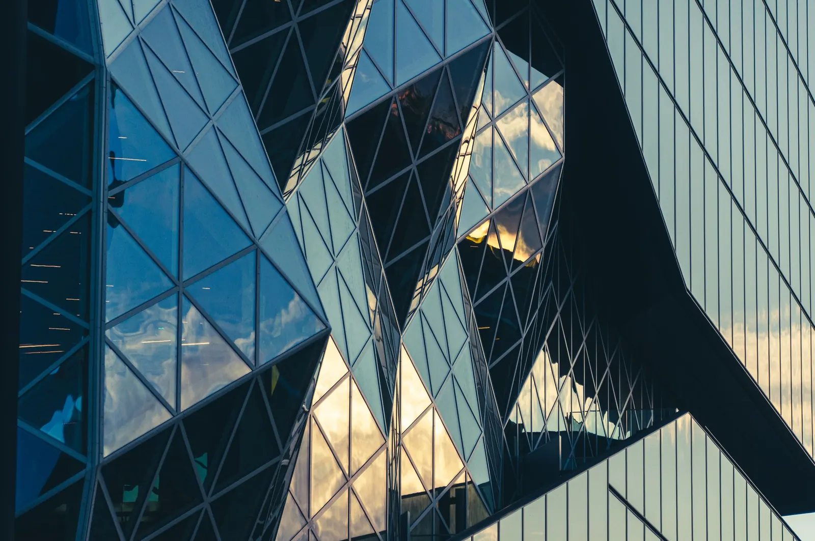 An abstract view of a sculptural glass facade reflecting the sky