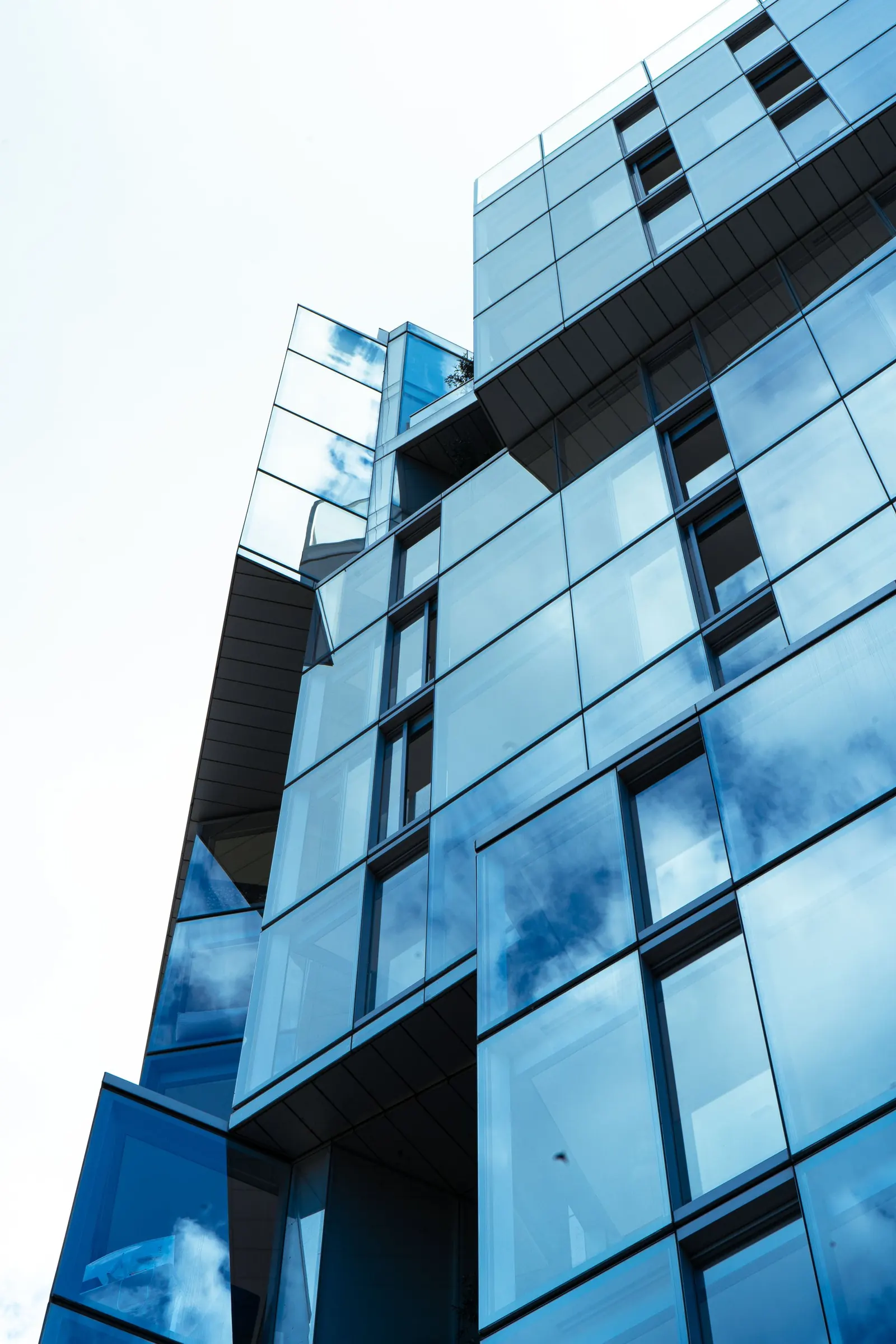 A blue glass curtain wall viewed from below