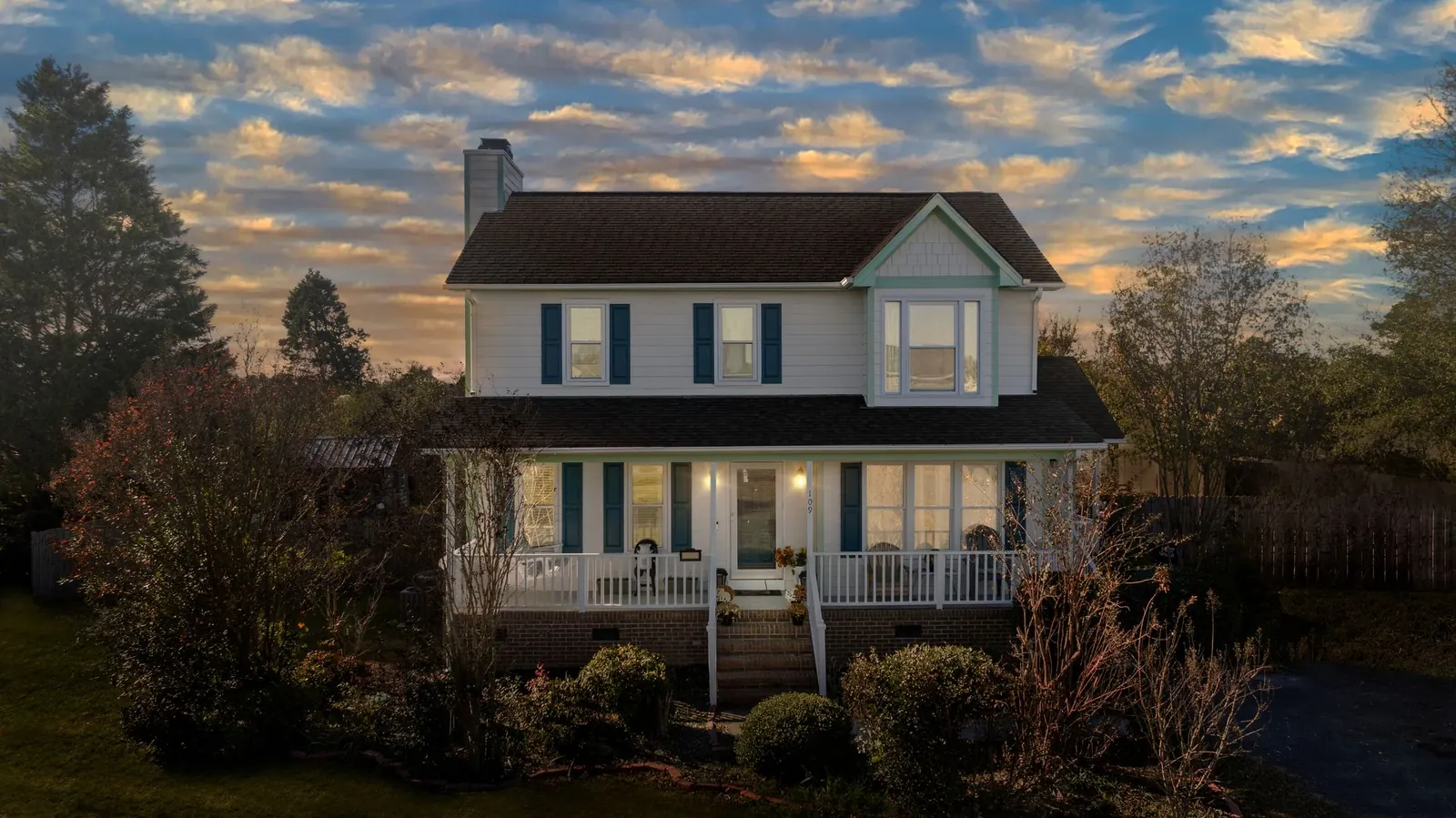A two-story house with a covered porch at sunset