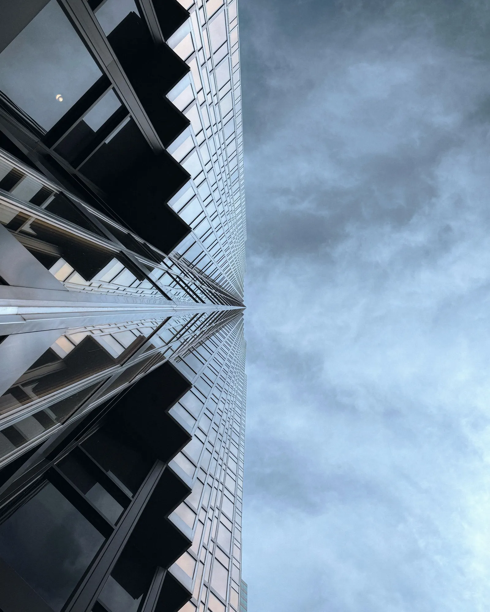 A modern glass tower rising into a blue sky
